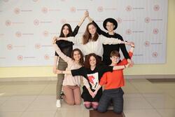 Six young women standing and kneeling, with their arms stretched in the shape of a star of David