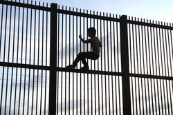 A Child Climbing a Fence at Mexico-US Border Cropped