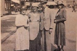 Black and white historical photograph of three women and a man standing in a city street