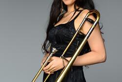 color photograph of a woman with long dark hair holding a trombone