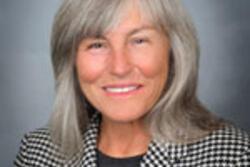 photo of a woman with shoulder-length light hair wearing a black and white checked jacket