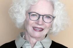 photograph of a woman with white hair wearing a dark sweater