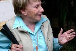 photograph of a woman with short blond hair talking with her hands, looking to the side