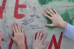 Children Place Hands on Wall with Message about Justice