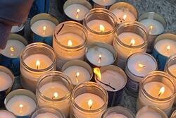 About 30 lit yahrzeit candles on the ground