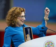 woman in blue dress with reddish hair at a podium accepting an award