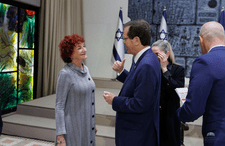 photograph of a woman with short curly red hair in a gray dress and a man in a blue suit