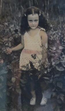colorized photo of a little girl with long hair surrounded by plants