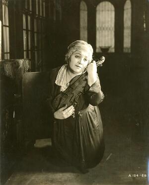 Vera Gordon cradling a violin in her arms close to her face