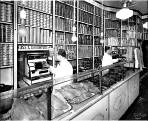 Joel Russ at the register behind the counter of Russ & Daughters, fish on display and cans lining shelves