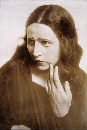 A promotional portrait of Hanna Rovina, looking concerned with her hand touching her face