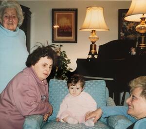 Family members gathered around baby sitting in a chair