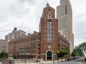 A brick building with a tower, situated on a street corner in New York City