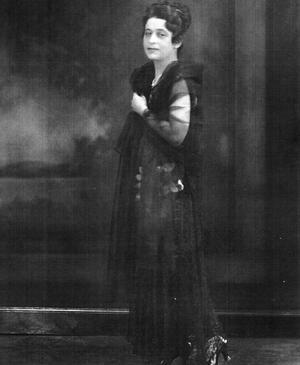 Studio portrait of actress Mirra Eitingon standing in a black dress
