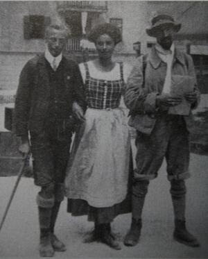 Emmy Eisenberg, arms linked with two men, all wearing boots, stockings, and short pants/a shorter skirt