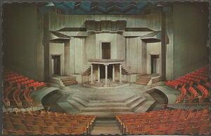 A drawing of a stage surrounded by red seats, with a grey, cubist set design featuring three doorways, several staircases, and a balcony held up by five pillars