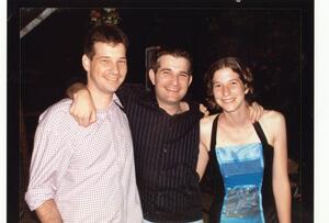 photograph of two young men and a young woman with their arms around each other