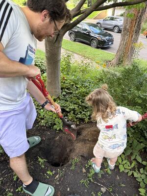 Father and daughter digging a hole for placenta burial