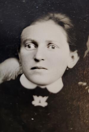black and white historical photo of a woman in a black dress with a white collar