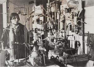 black and white photograph of a woman in a lab surrounded by lab equipment
