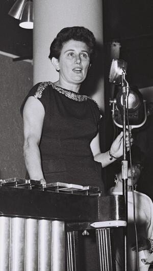 black and white photograph of a woman in a dark dress at a microphone