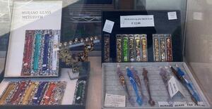 Display window at glass shop in Venice featuring mezuzot and other religious objects.