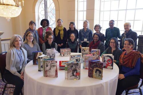 Group of seated and standing women around a table displaying book-form artworks