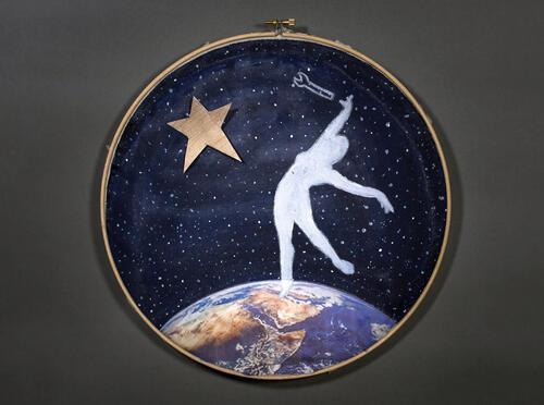 Embroidery hoop depicting a woman's silhouette on a navy background on the arc of planet Earth reaching toward toward a star