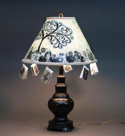 Lampshade adorned with image of a tree, photos of family members, and small dangling books