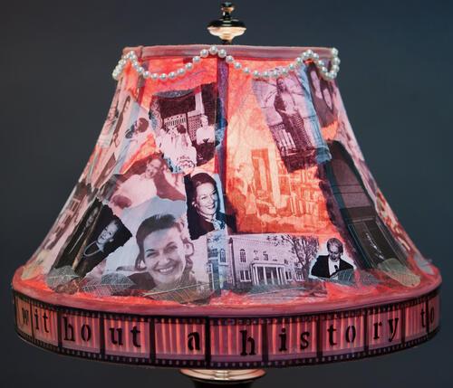 Lampshade decorated with photos, faux pearls, and text at the base that reads "without a history" 