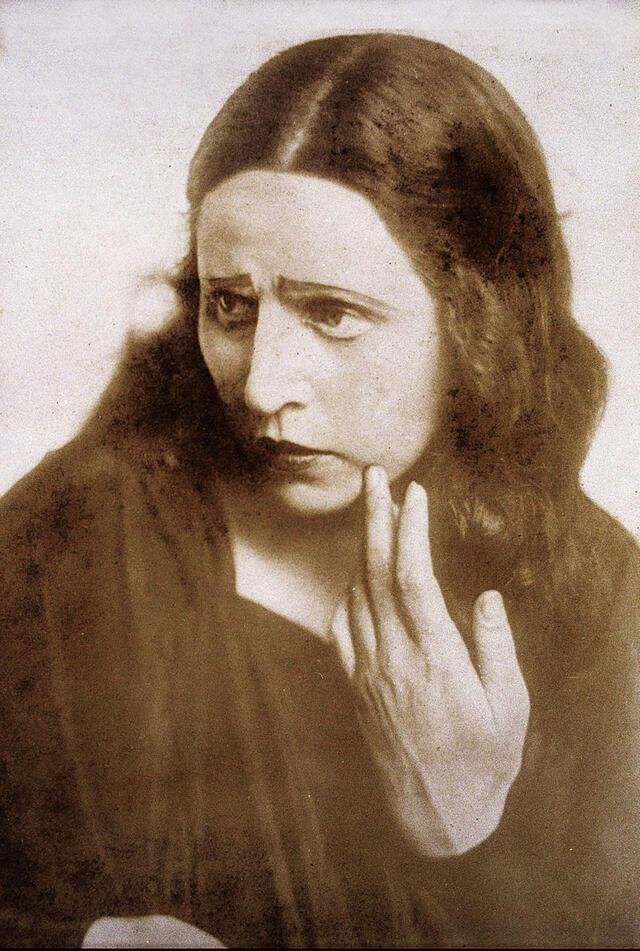 A promotional portrait of Hanna Rovina, looking concerned with her hand touching her face