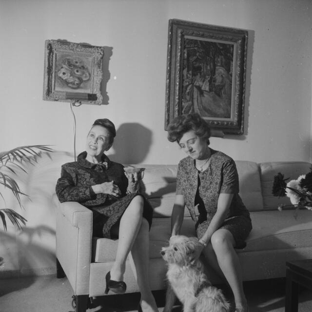 Batsheva de Rothschild and Martha Graham sitting on a sofa with a dog sitting at their feet