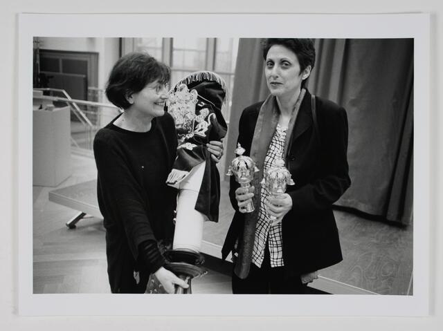 Miriam Rosengarten holding a Torah, partially removing its cover, and Rina Otterbach holding two Torah crowns