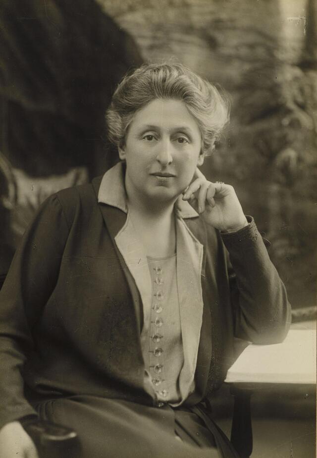 Cécile Brunschvicg sitting at a desk, with her elbow resting on an open book