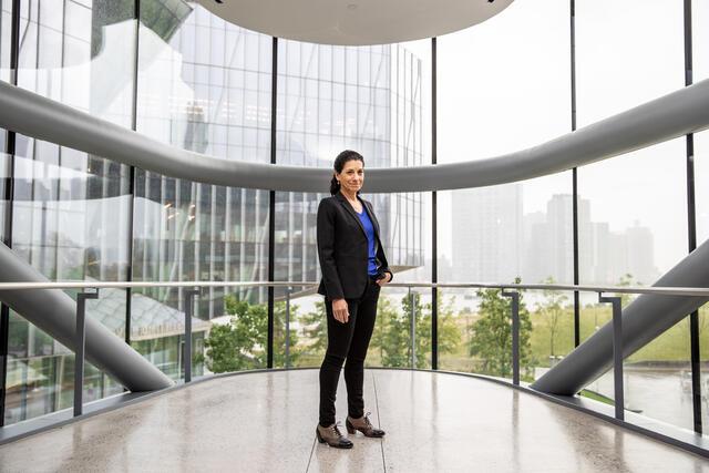 Deborah Estrin standing center in front of wall of glass looking outside, 2018