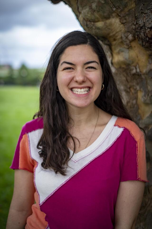 Photo of Lilah Peck, in front of tree wearing geometric shirt with a white, orange, and pink pattern.