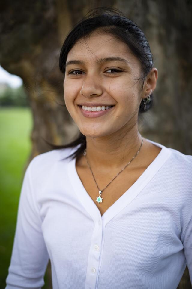 Photo of Shoshanna Hemley, in front of a tree wearing a white shirt