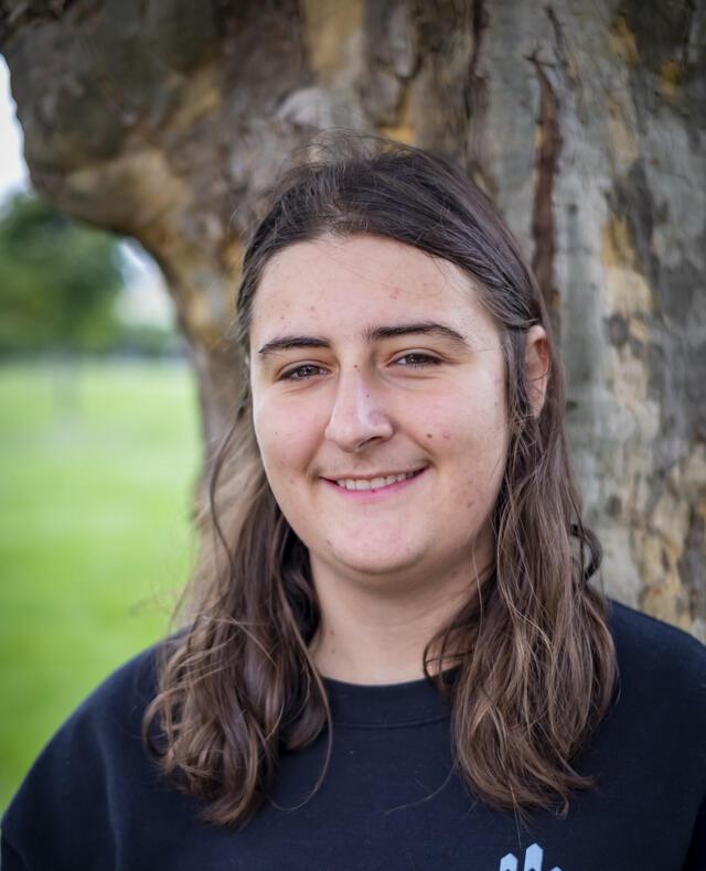 Photo of Ellanora Lerner, in front of a tree wearing a dark blue hoodie.