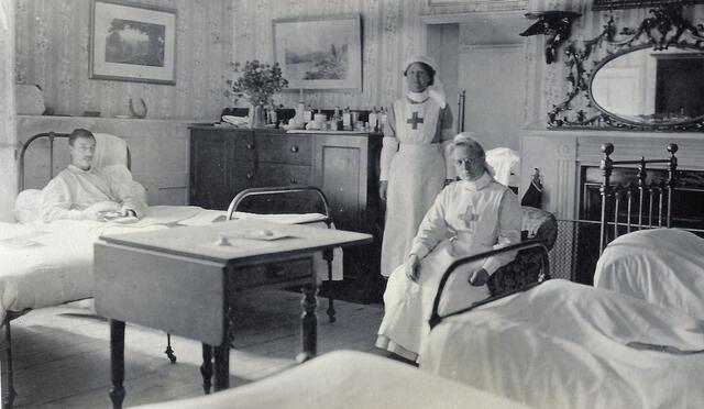 A man lying in a hospital bed with two nurses in uniform