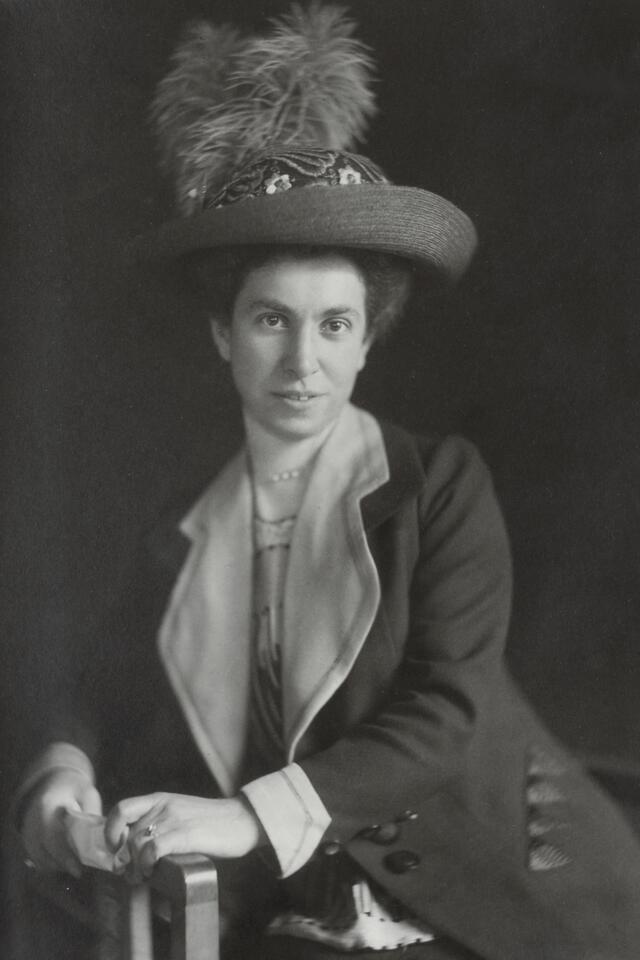 Josephine Levy-Rathenau, dressed in a hat and coat, leaning against an armrest