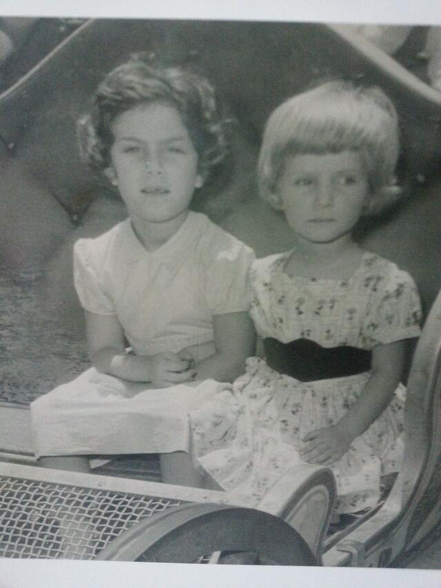 Marjorie Agosin and her sister as children, wearing dresses and sitting in a small sled or cart