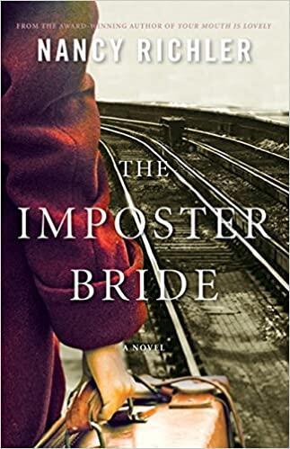 Close photograph of a woman’s arm, in a red wool coat, holding a suitcase beside train tracks