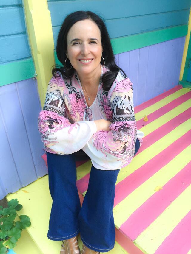 Rudio Behar sitting on a colorfully-painted pastel porch