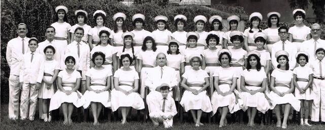 A large group of people in white costume, wearing hats or kippahs; primarily women, but including a few men and children as well