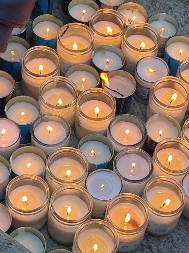 About 30 lit yahrzeit candles on the ground