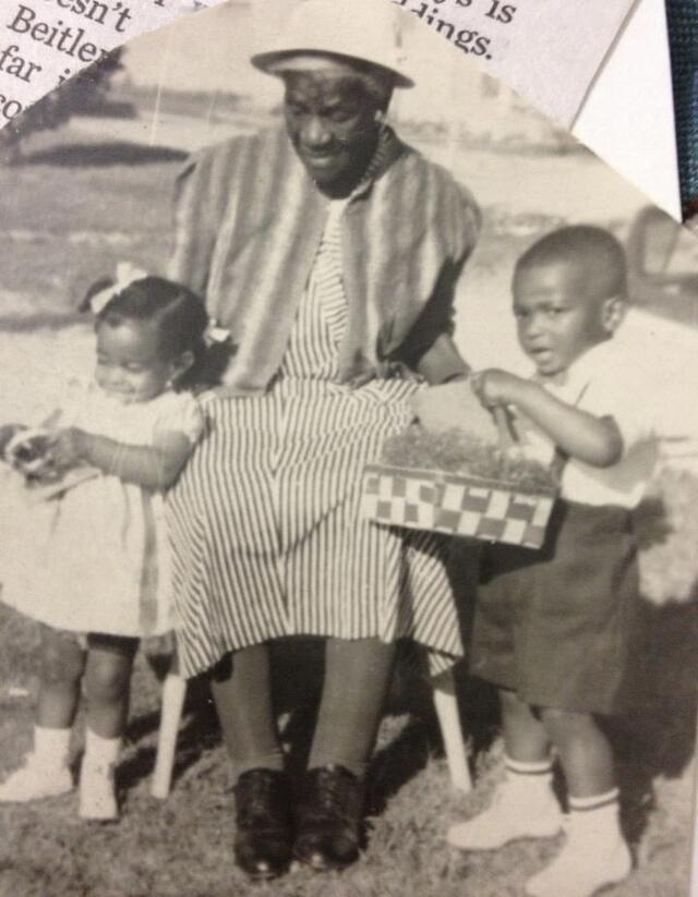 Black and white photo of Black woman sitting with grandchildren on either side of her
