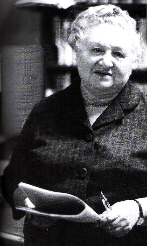 black and white photograph of an older woman with white hair holding a newspaper