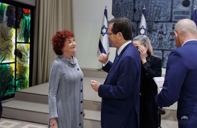 photograph of a woman with short curly red hair in a gray dress and a man in a blue suit