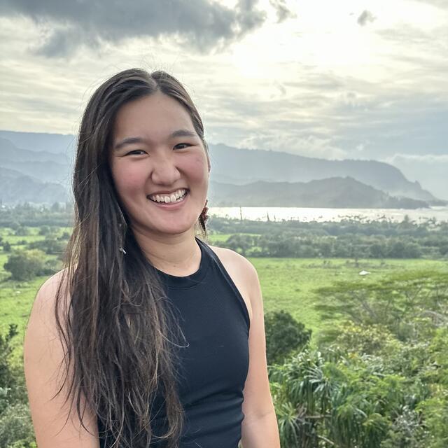 photograph of an Asian woman with long hair against a rural mountainous background