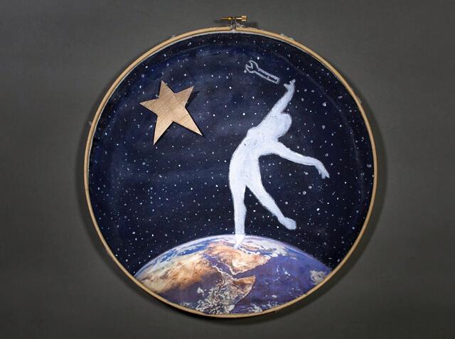 Embroidery hoop depicting a woman's silhouette on a navy background on the arc of planet Earth reaching toward toward a star